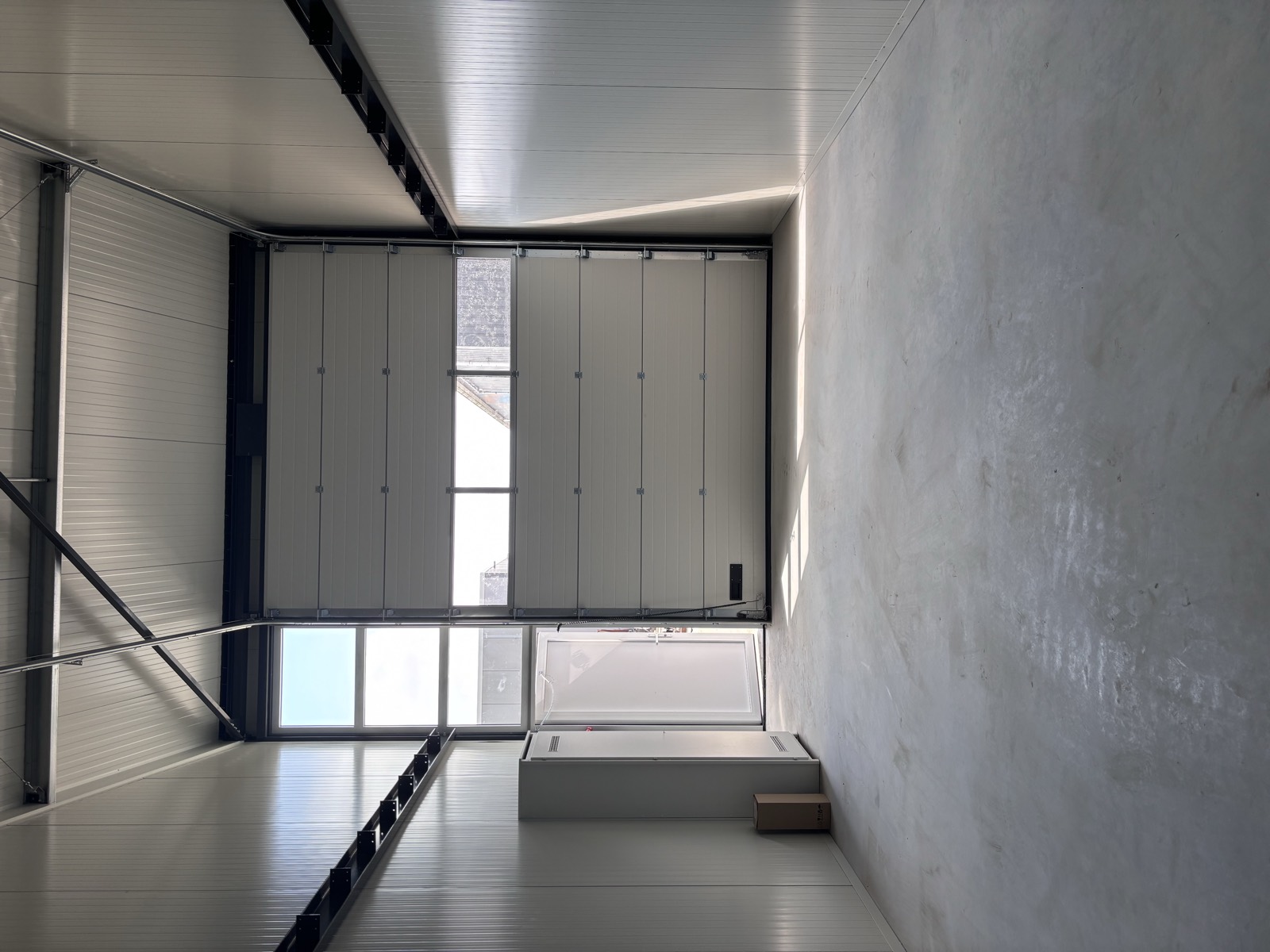 Interieur bedrijfsunit Burgum met geïsoleerde sectiedeur, loopdeur en betonvloer